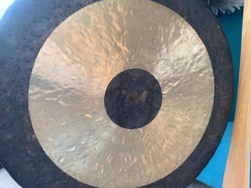 Großer TamTam (80cm Durchmesser) aus Metall, der mit einem Schlegel angeschlagen wird und tiefe, vibrierende Klänge erzeugt.